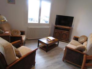 uma sala de estar com sofás e uma televisão de ecrã plano em gîte de la Claveille em Bergerac