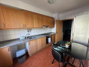 a kitchen with wooden cabinets and a table and a sink at FUNCHAL APARTMENT WITH POOL - Garajau 2 in Caniço