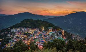 vistas a una ciudad en las montañas al atardecer en Summit Namnang Courtyard & Spa, en Gangtok