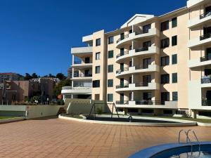 a large apartment building with a pool in front of it at FUNCHAL APARTMENT WITH POOL - Garajau 2 in Caniço