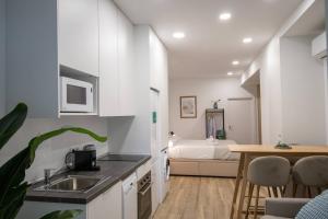 uma cozinha com armários brancos e um quarto com uma cama em Cid Flats by Concept em Valência
