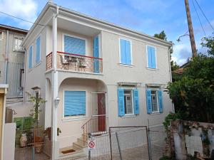 Casa blanca con ventanas azules y valla en Old Town House at Lefkada city, en Lefkada