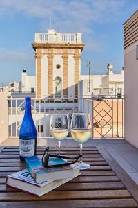 VG - Villa de Andas suites في كاديز: كأسين من النبيذ وكتاب على طاولة