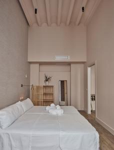a bedroom with a large bed with white sheets at VG - Villa de Andas suites in Cádiz