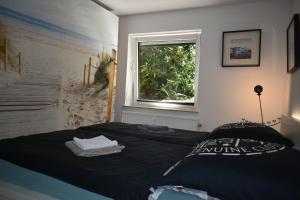 a bedroom with a black bed with a window at Möwennest am Twedter Holz in Flensburg