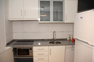 a kitchen with white cabinets and a sink at Pátio da Caetana in Freineda