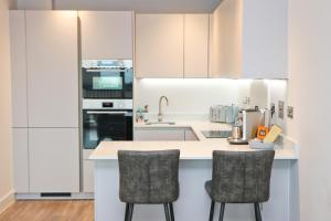 a kitchen with white cabinets and two bar stools at Sea view apartment, first floor in Saint Merryn