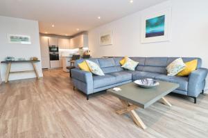 a living room with a blue couch and a table at Sea view apartment, first floor in Saint Merryn