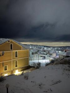 Домик у гор في Besqaynar: منزل أصفر في الثلج مع مدينة في الخلفية