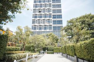 Ramada By Wyndham Bangkok Sukhumvit 87 في بانكوك: اطلالة على مبنى طويل من حديقة بها اشجار