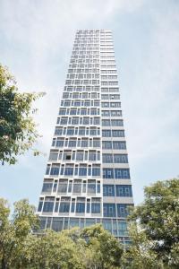 曼谷的住宿－Ramada By Wyndham Bangkok Sukhumvit 87，一座高大的白色建筑,前面有树木