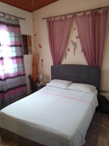 a bedroom with a white bed with pink curtains at Amalia in Áyios Ilías