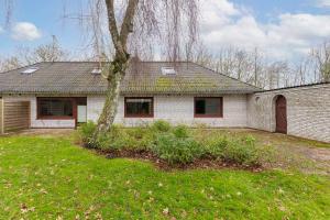 a white brick house with a tree in the yard at De Maade in Enge-Sande