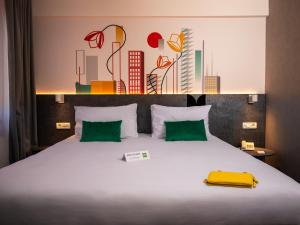 a bedroom with a large white bed with green pillows at ibis Styles Pitesti Arges in Piteşti