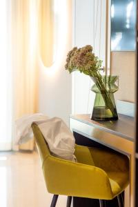 a yellow chair next to a desk with a vase of flowers at Hotel Mondial in Rimini