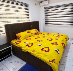 1 cama con edredón y almohadas amarillos en Signature Residence, en Calabar
