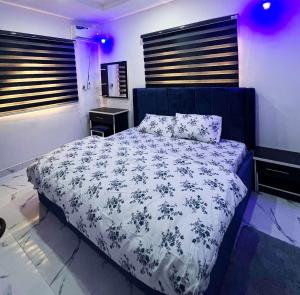 Schlafzimmer mit einem Bett mit einer blauen und weißen Bettdecke in der Unterkunft Signature Residence in Calabar