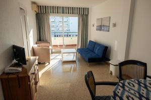 a living room with a blue couch and a television at Apartamentos Buensol in Torremolinos