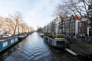 einen Fluss mit Booten in einer Stadt mit Gebäuden in der Unterkunft Cozy B&B Prinsengracht in Amsterdam