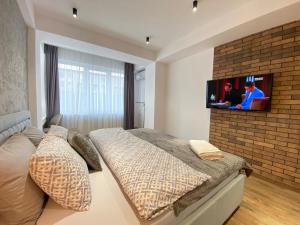 um quarto com uma cama e uma televisão numa parede de tijolos em Large and Cozy Apartment in the Center em Chisinau