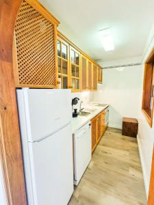 a kitchen with a white refrigerator and wooden cabinets at Apartamento Sweet Aroma in Breña Baja