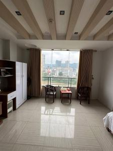 a bedroom with a large window with a table and chairs at Thiên Thiên Thanh in Lao Cai