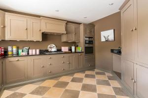 a kitchen with wooden cabinets and a checkered floor at Large Historic Secret Hideaway in Moreton in Marsh