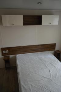 a bedroom with a white bed with a wooden headboard at mobil home in Sainte-Reine-de-Bretagne
