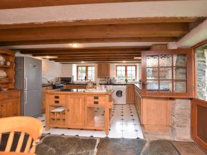 a large kitchen with wooden cabinets and a refrigerator at 3 Bed in Boscastle 75145 in Boscastle