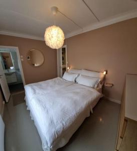 una camera da letto con un grande letto bianco e un lampadario a braccio di Mulen: Lokal sjarm, naturopplevelser i Bergen a Bergen