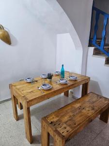 een houten tafel en bank in een kamer bij App 2 chambres piscine privative 600m plage in Mezraya