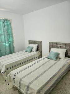 two beds sitting next to each other in a room at App 2 chambres piscine privative 600m plage in Mezraya