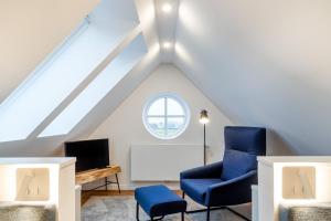 um quarto no sótão com uma cadeira azul e uma televisão em Küstenglück, neu mit Balkon und Infrarotkabine! em Greetsiel
