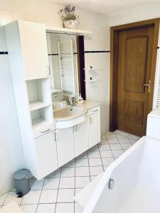 a white bathroom with a sink and a mirror at Kapitäns Hus 2 mit Infrarotsauna und großem Garten in Graal-Müritz +14 photos