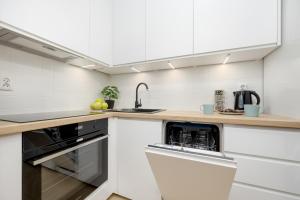 a white kitchen with a sink and a dishwasher at Bukowińska Apartments with Balcony and Parking and Swimming Pool by Renters in Warsaw
