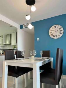 uma mesa com cadeiras e um relógio numa parede azul em Perfect Ground Floor with Sea View em Punta Prima