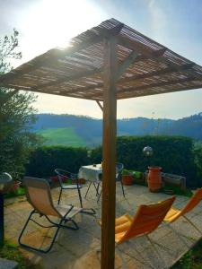 a wooden pergola with chairs and a table at La Casina di Ancicucco 2 in San Gimignano +16 photos
