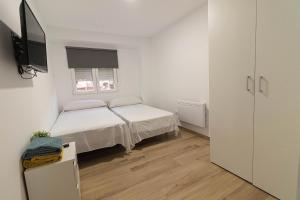 a small white bedroom with a bed and a window at ¡A disfrutar de Valencia! in Valencia