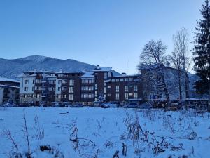 a snow covered field in front of a building at Mountain View Resort - Apartment B45 in Bansko