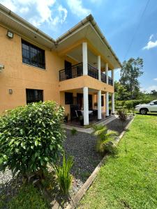 uma casa com uma varanda e um quintal em Cinnamon House em Kisumu