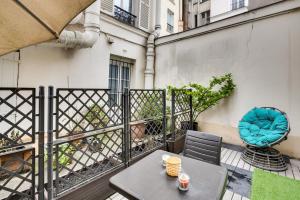 eine Terrasse mit einem Tisch und Stühlen auf dem Balkon in der Unterkunft Chic studio dans l'hypercentre parisien in Paris