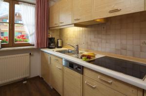 a kitchen with wooden cabinets and a sink and a window at Landhaus Exclusiv in Bolsterlang