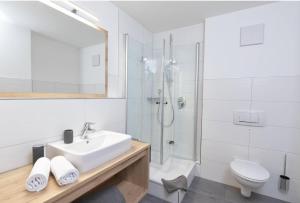a white bathroom with a sink and a shower at Landhaus Exclusiv in Bolsterlang