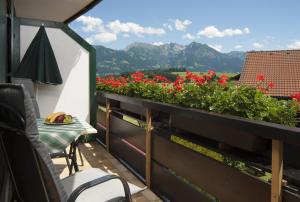 a balcony with red flowers and a table and chairs at Landhaus Exclusiv in Bolsterlang