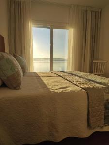a bedroom with a large bed with a large window at Apartamentos La Toja in O Grove