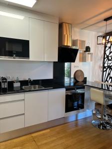 une cuisine avec des armoires blanches et des comptoirs noirs dans l'établissement Superbe studio Paris La Défense, à La Garenne-Colombes