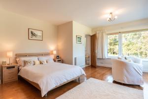 1 dormitorio con cama blanca y ventana en A split-level spacious home with sea & mountain views, en Templenoe