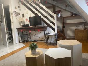 a living room with a television and a desk with a table at Aux petits cœurs de COLMAR CENTRE WIFI in Colmar