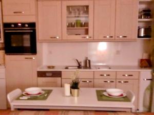 a kitchen with white cabinets and a table with two plates at Schöne Ferienwohnung mit Balkon und Garten in Nonnweiler