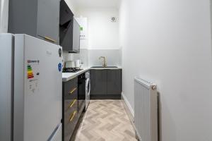 a small kitchen with a refrigerator and a sink at Coatbridge Apartment in Coatbridge